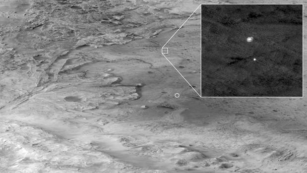 in this image, the descent stage holding NASA�s Perseverance rover can be seen falling thorough the Martian atmosphere, its parachute trailing behind